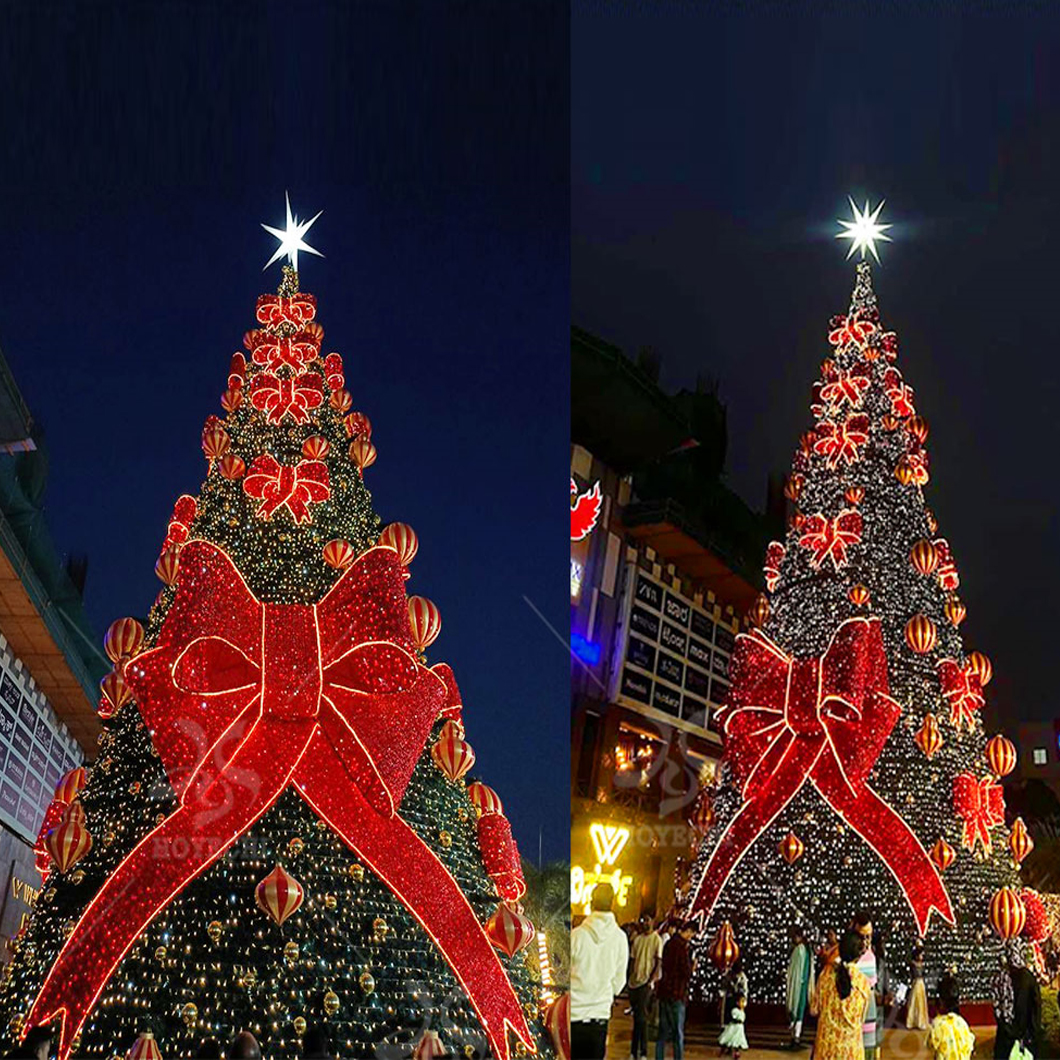 HOYECHI outdoor Christmas tree with giant red bow and warm white lights in a commercial plaza at night