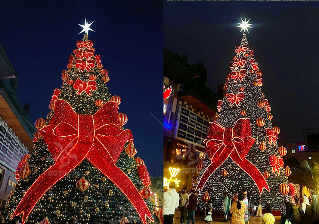 Illuminated commercial Christmas tree with giant red bow for outdoor mall and public holiday display