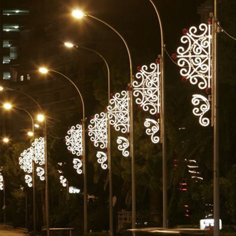 Des motifs lumineux répétés sont installés le long des deux côtés d'une large route urbaine, avec un rythme festif et un ordre visuel clairs.