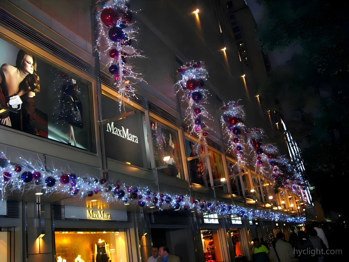 Commercial building facade with continuous Christmas entrance lighting, doorway garland decoration, and illuminated vertical festive elements