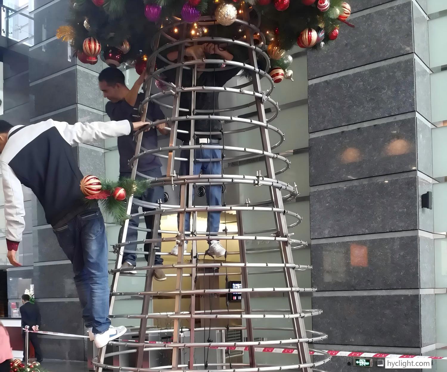 Workers installing a large commercial Christmas tree metal frame structure for a holiday decoration project