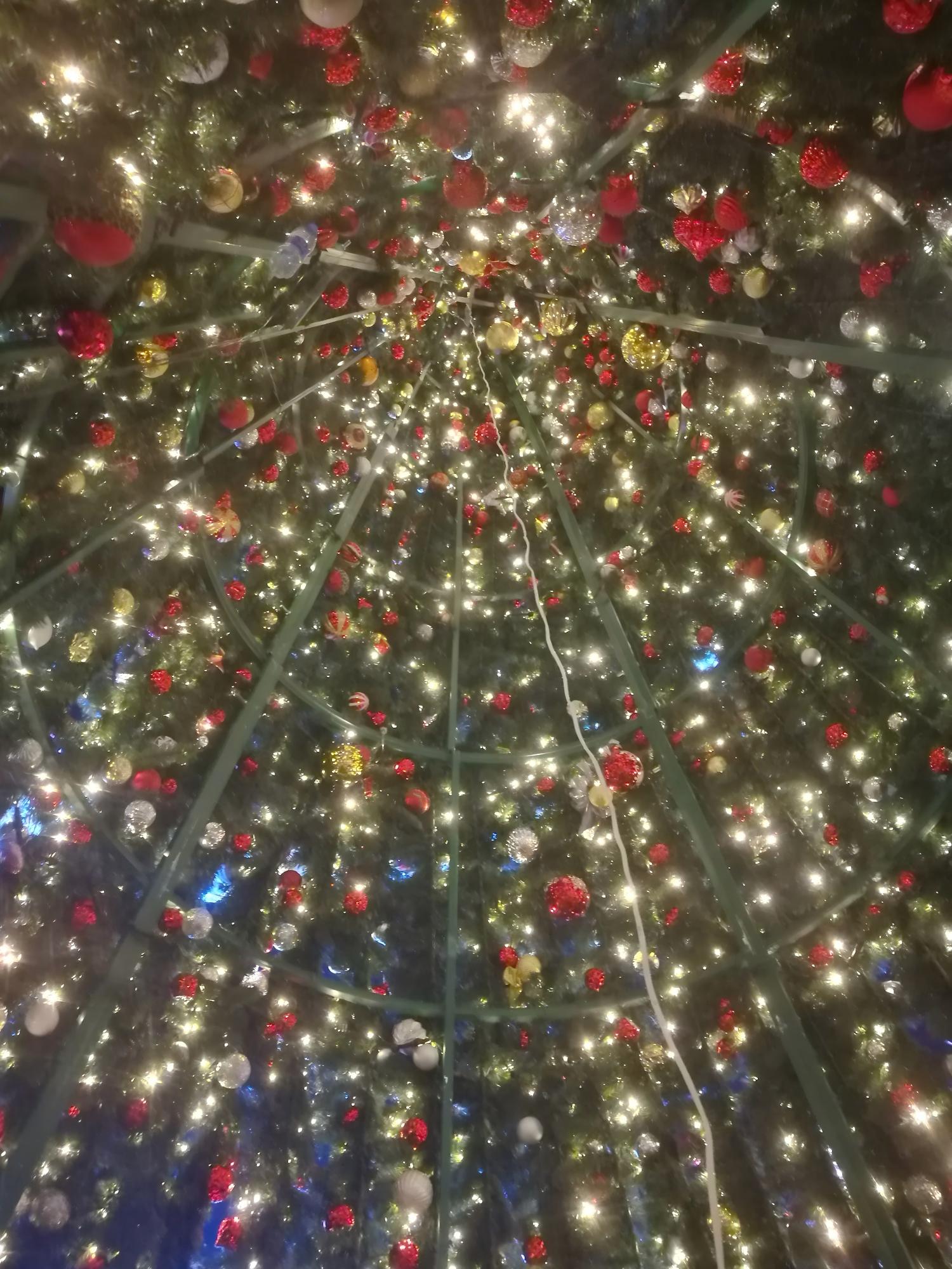 Vista interior de un árbol de Navidad comercial de estructura cónica que muestra el armazón estructural, la iluminación y la instalación de adornos.