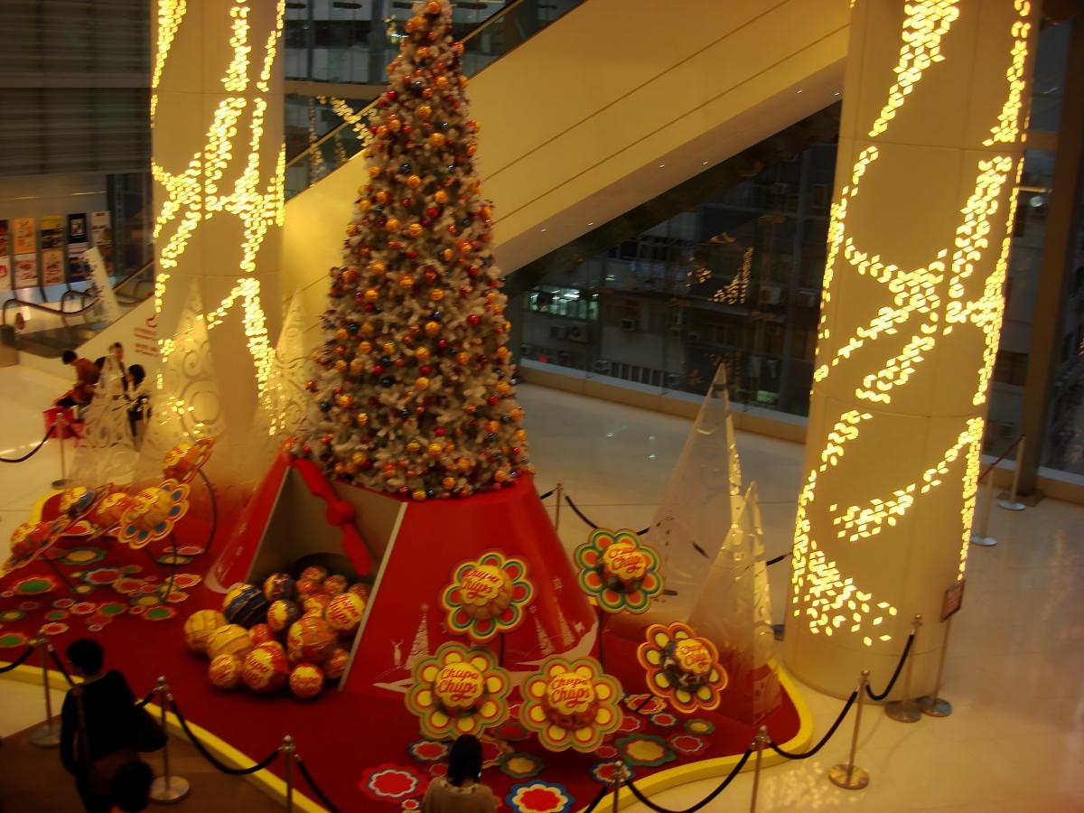 Escaparate navideño en el atrio de un centro comercial con un árbol decorado, atrezzo festivo temático y un montaje navideño apto para fotografías.