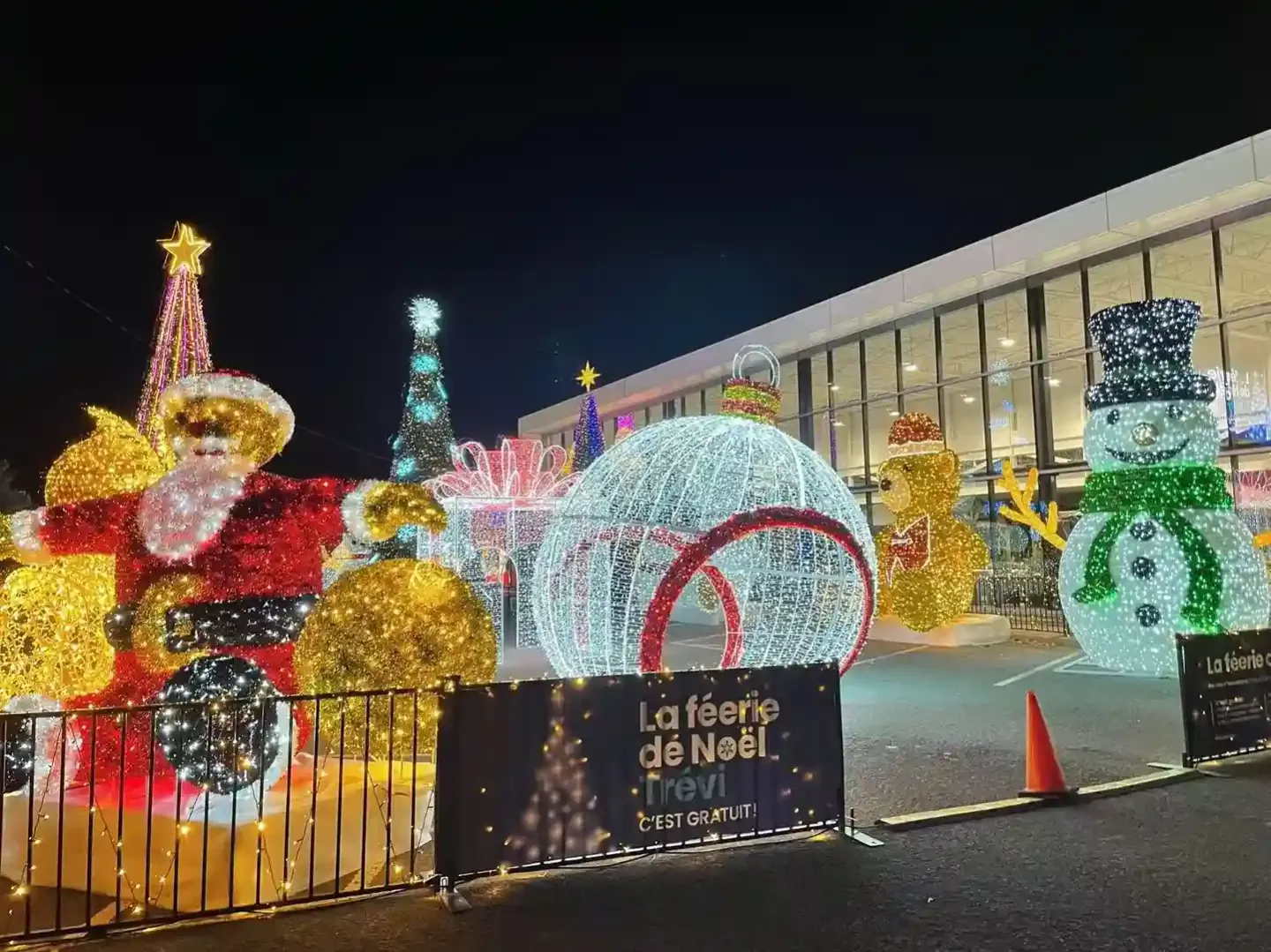 Illuminated Christmas display structures outside a building at night