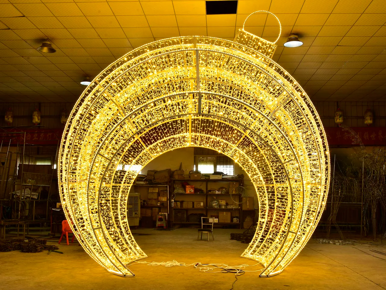 Large illuminated ornament-shaped frame with a central opening photographed in a workshop
