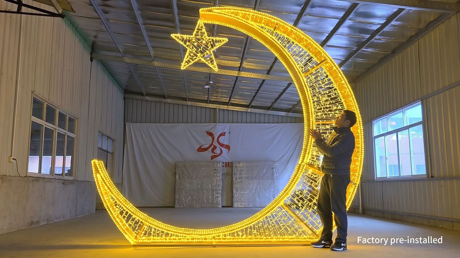 Illuminated crescent-and-star display standing in a workshop beside a person