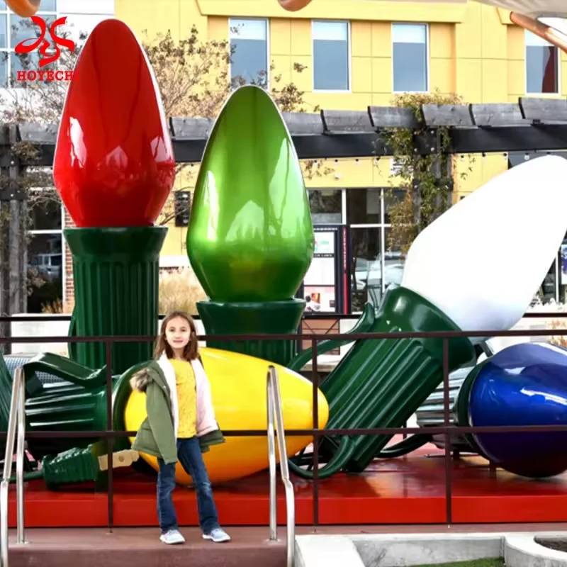 Large red green and white Christmas bulb decorations shown beside a person for scale