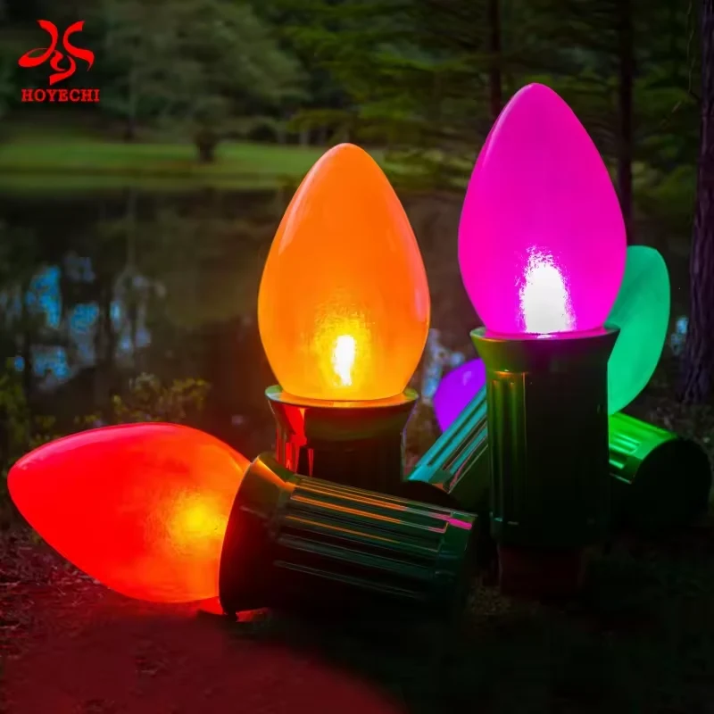 Standing and side-lying oversized Christmas light bulb sculptures in a landscaped setting