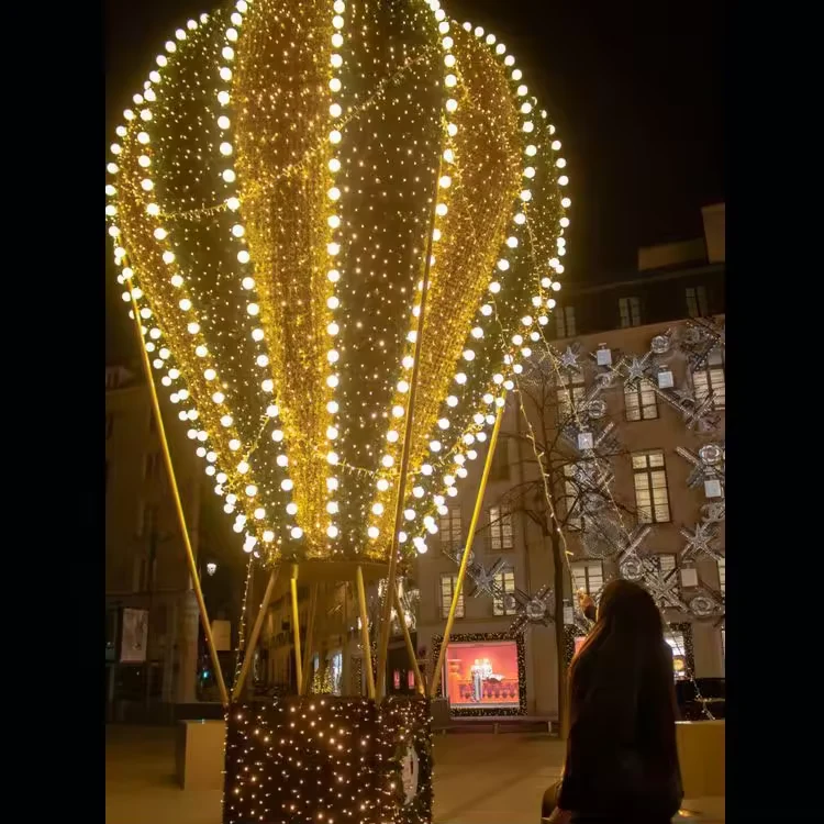 Tall warm white hot air balloon light display beside visitors