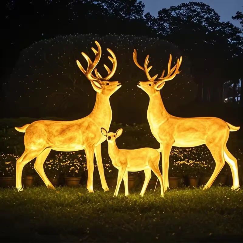Glowing fiberglass deer family arranged outdoors at night