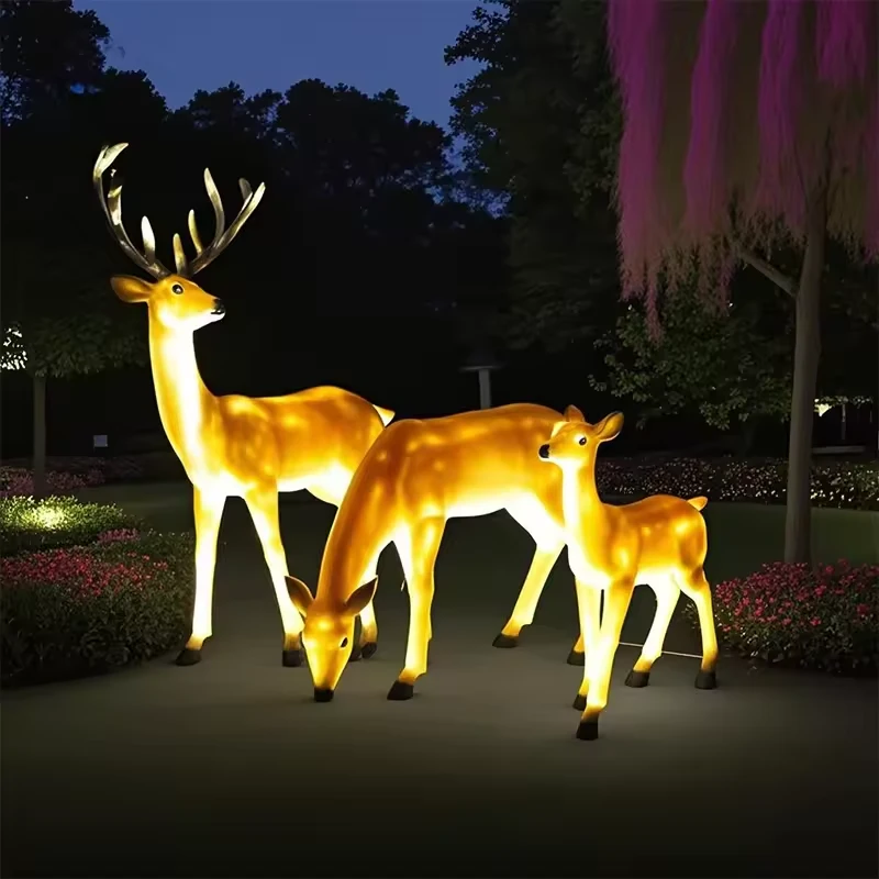 Illuminated standing and grazing fiberglass deer group
