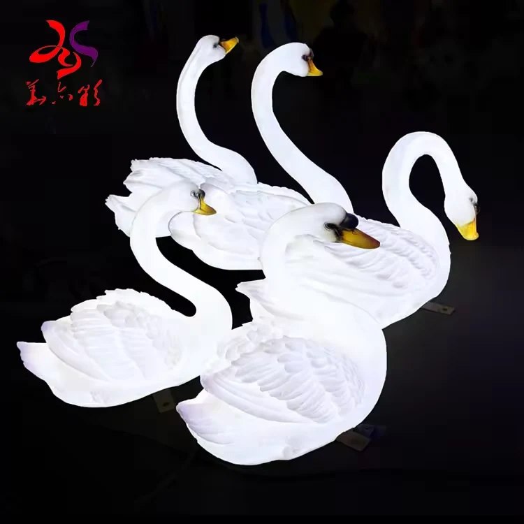 Group of white illuminated fiberglass swan sculptures in different poses