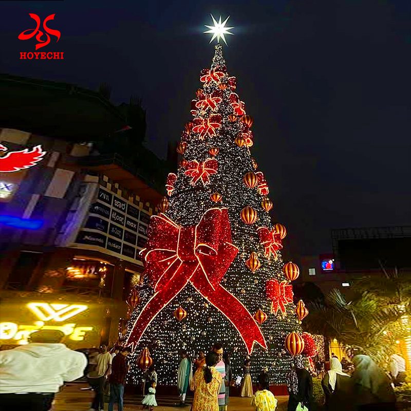 Arbre de Noël géant personnalisé pour l'extérieur, avec nœud lumineux et ornements suspendus, pour un affichage commercial des fêtes de fin d'année