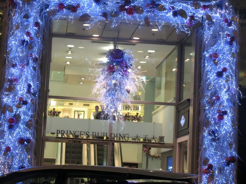 Entrada de edificio comercial con envoltura de guirnalda navideña en el portal, decoración de marco iluminado y centro de mesa festivo suspendido
