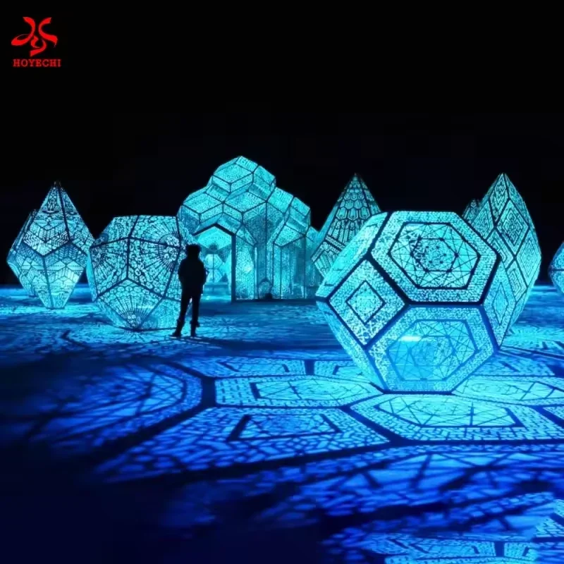Blue illuminated geometric sculptures with patterned light across the ground