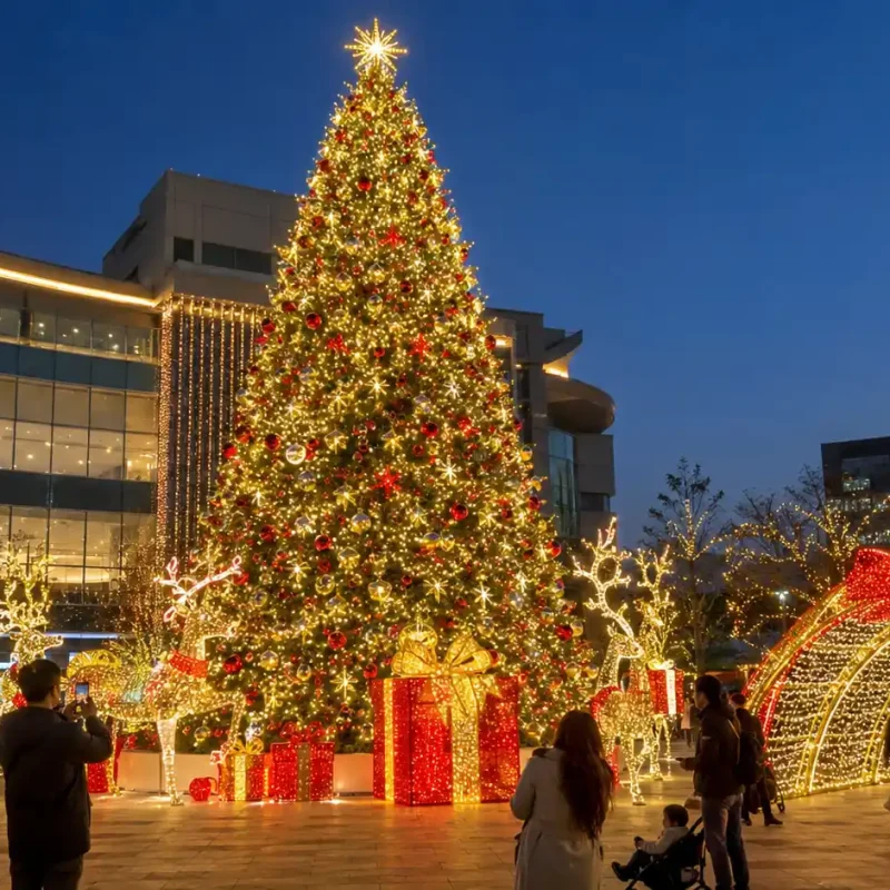Grande árvore de Natal comercial com densas luzes LED brancas quentes e multicoloridas numa praça da cidade à noite
