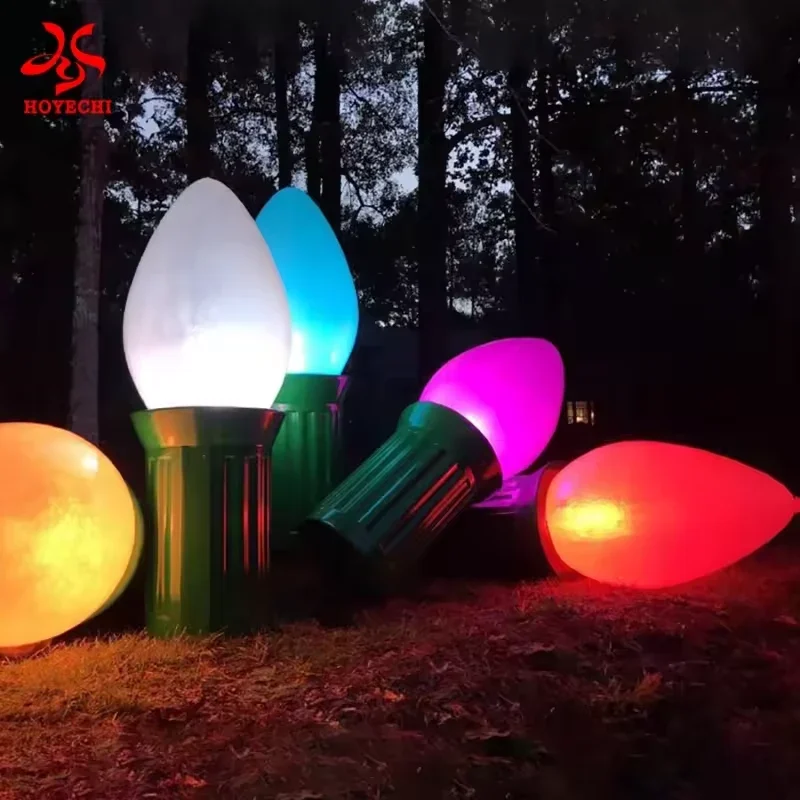 Oversized illuminated Christmas bulb sculptures with green bases in a colorful outdoor display