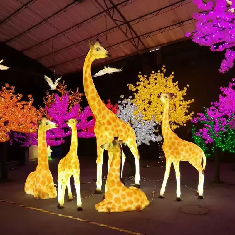 Illuminated giraffe sculptures with yellow spotted bodies in standing and seated poses