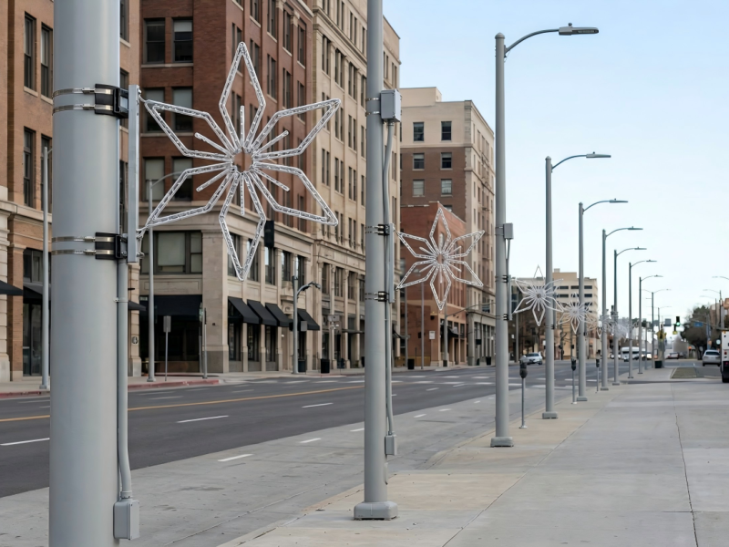 Technicians installing pole mounted street motif lights on a city light pole using no-drill brackets and protective straps