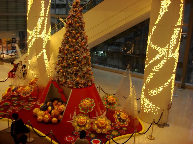 Escaparate navideño en el atrio de un centro comercial con un árbol decorado, atrezzo festivo temático y un montaje navideño apto para fotografías.